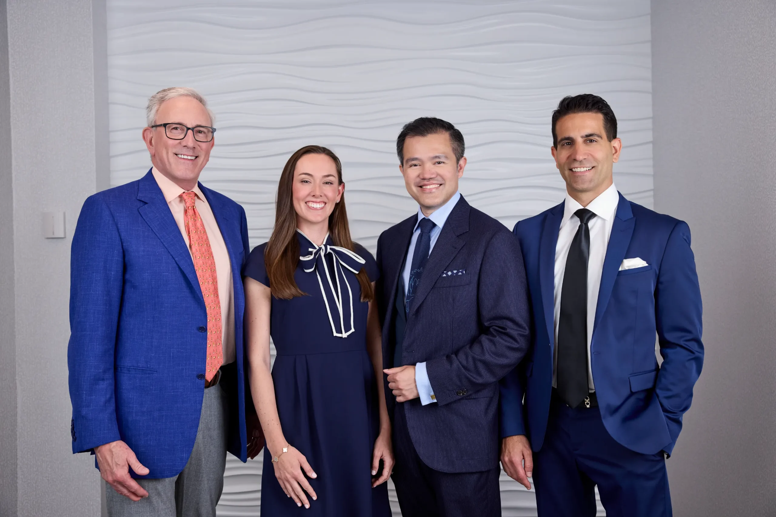 The full team of doctors, in their white coats, standing together smiling in an operating room
