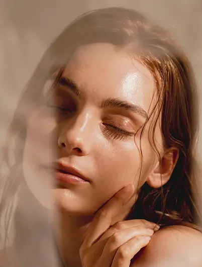 a woman in a beam of sunlight with eyes closed, touches her face