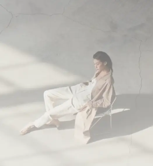 woman sits relaxed in a chair, slumped down with her legs stretched out in front of her