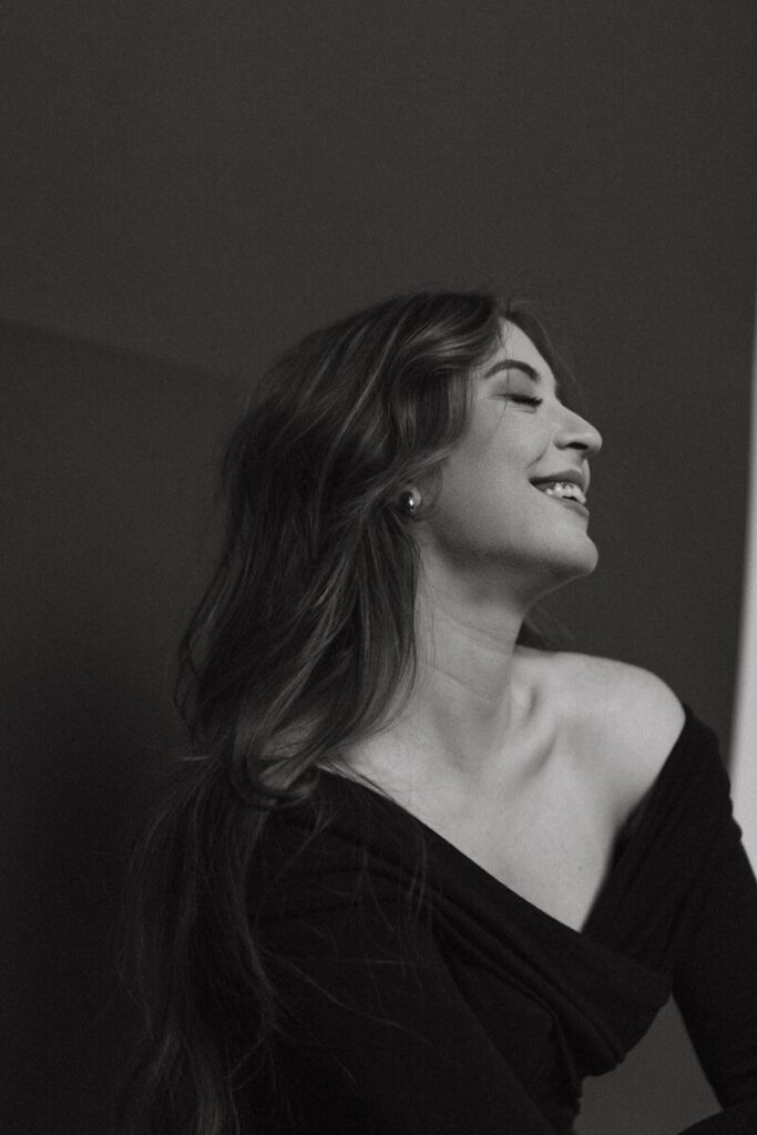 A woman in a black dress looking out a window