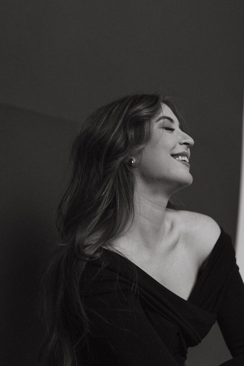 A woman in a black dress looking out a window