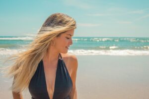 woman in black tank top standing on beach -- should you consider a breast lift?